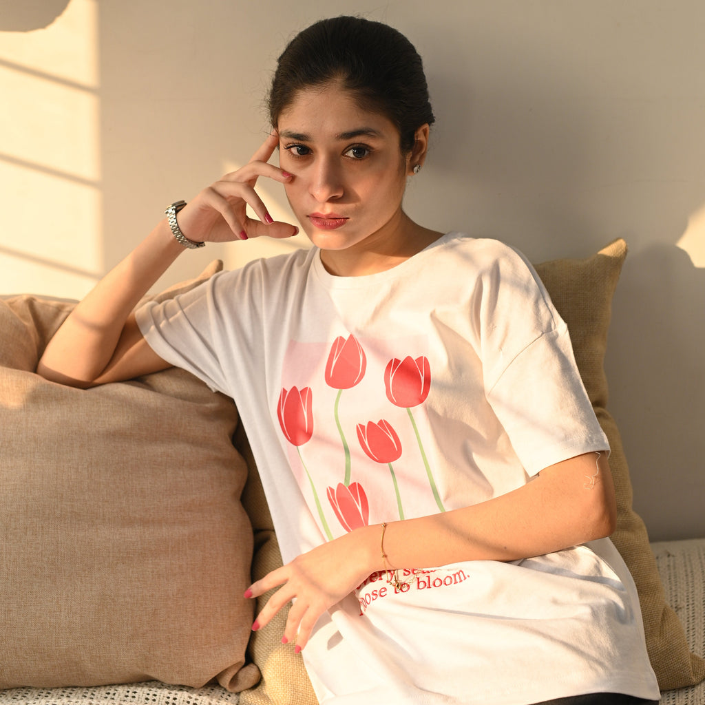 Person wearing a white shirt with red tulip design on a plain background
